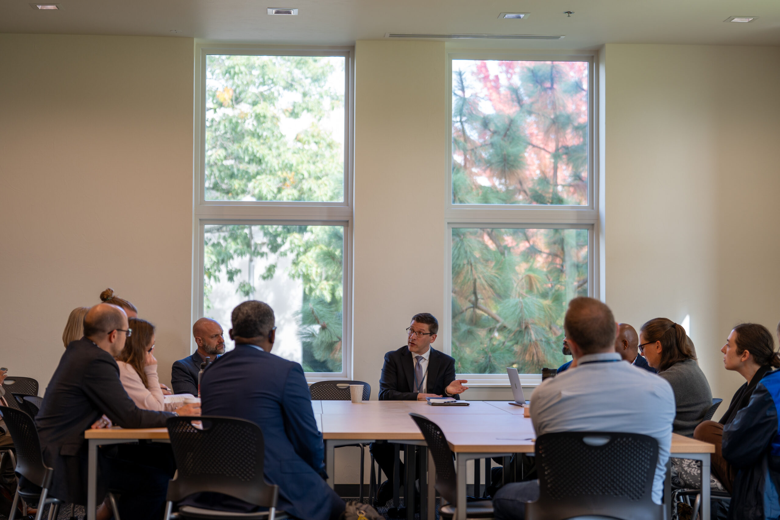 A group of people seated around a large table in discussion.